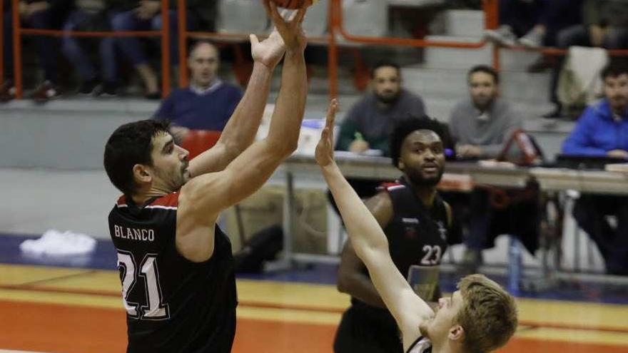 Saúl Blanco lanza a canasta ante la oposición de un jugador del Tormes y la mirada de Nelson Yengue.