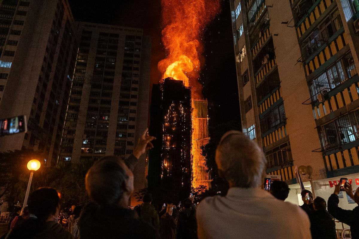 People look at flames engulfing a building after a fire broke out at Wang Fuk Court, a residential estate in the Tai Po district of Hong Kongs New Territories, Wednesday, Nov. 26 2025. (AP Photo/Chan Long Hei)