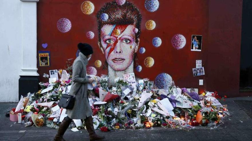 Una mujer pasa ante un mural de Bowie cubierto de flores en Londres.