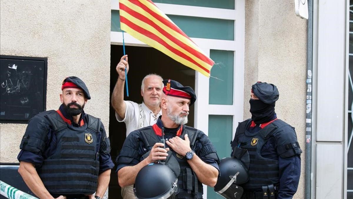 Un hombre con una 'senyera', junto a unos agentes en la operación contra los CDR en Sabadell