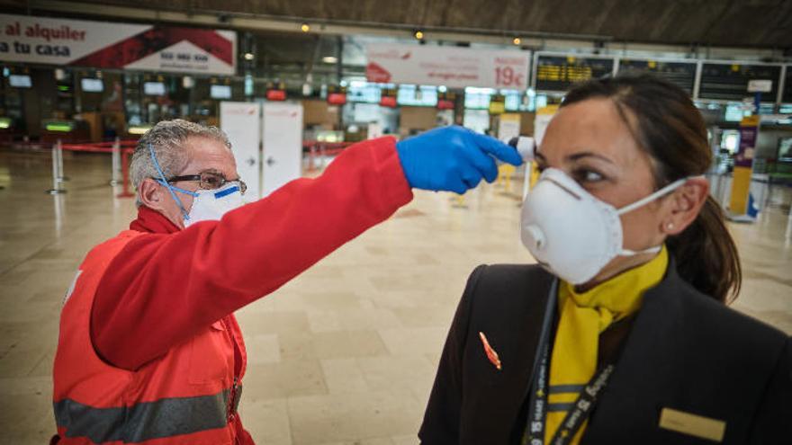 Un voluntario de Cruz Roja toma la temperatura a una azafata de vuelo en el Aeropuerto de Tenerife Norte.