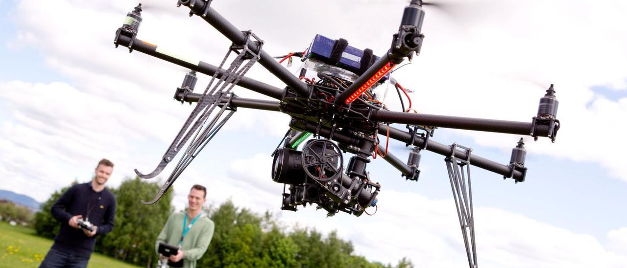 Dos personas controlan el vuelo de un dron.