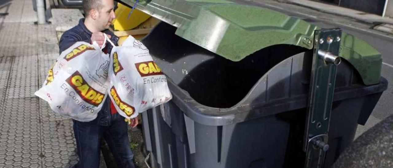 Un vecino de Lalín deposita dos bolsas de basura en un contenedo de orgánicos. // Bernabé/Luismy