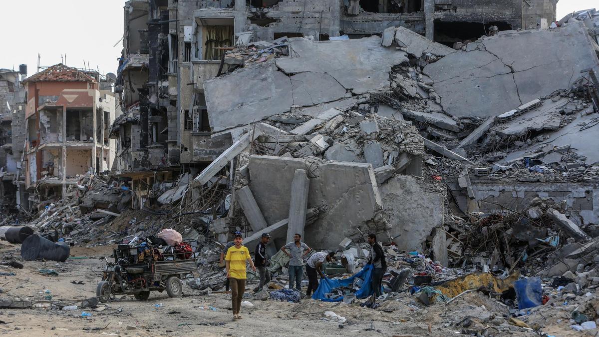 Varios hombres en Jan Yunis (Gaza) junto a las ruinas de un edificio destruido en un bombardeo de Israel.