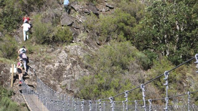 Arriba, puente tibetano de Porto. A la izquierda, varias personas observando diferentes paneles turísticos de información. | ARACELI SAAVEDRA