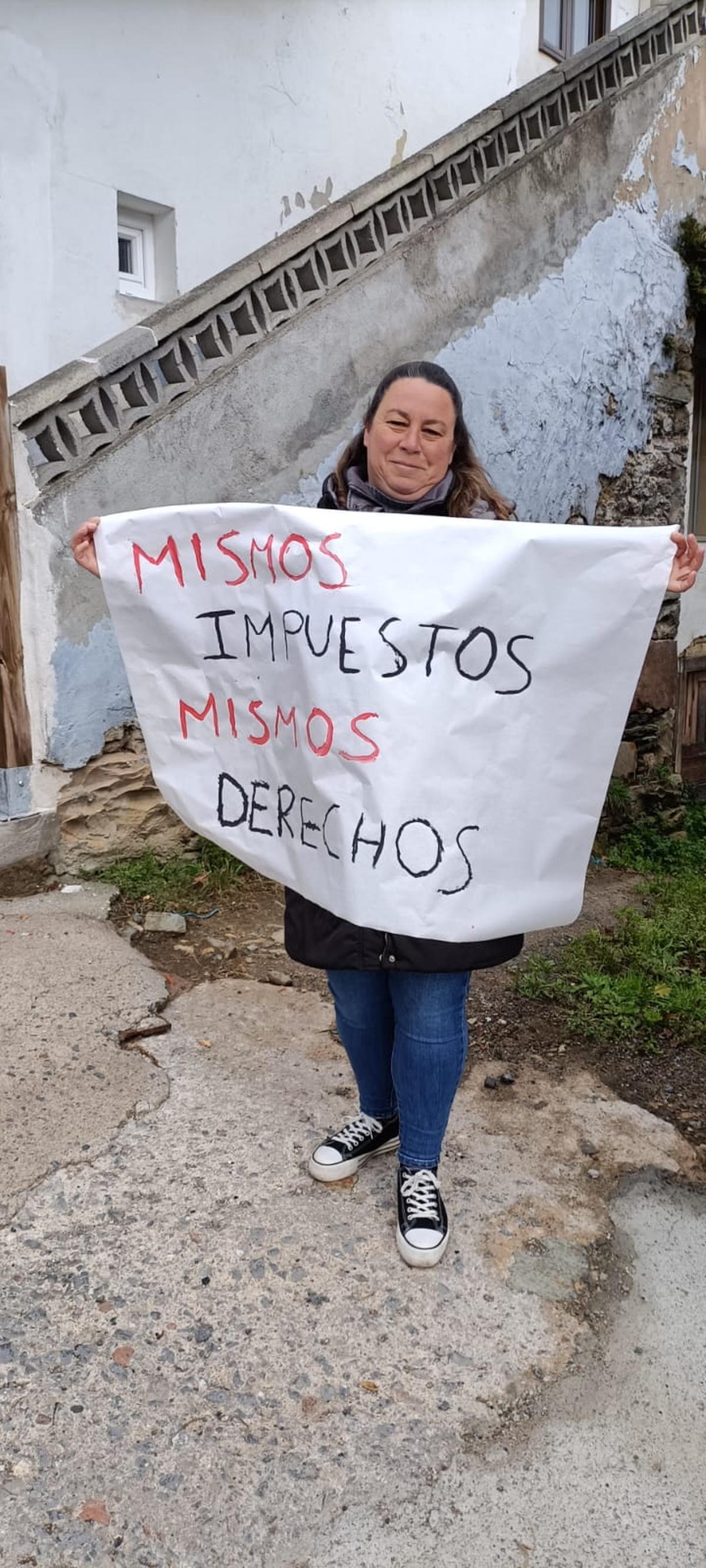 María del Carmen García en el exterior de la escuela con una pancarta.