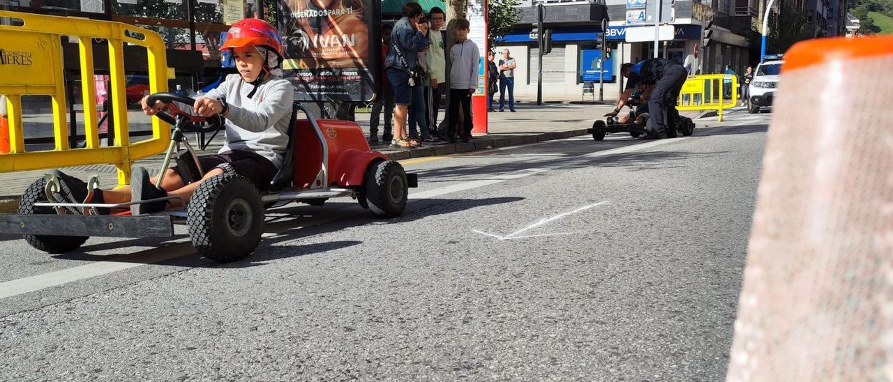 Arriba, uno de los escolares que participaron en la actividad del karting. En el centro, el agente José Manuel Fanjul observa como los niños manejan los karts por el circuito. Junto a estas líneas, el histórico autobús expuesto por el Ayuntamiento de Mieres. | A. Velasco