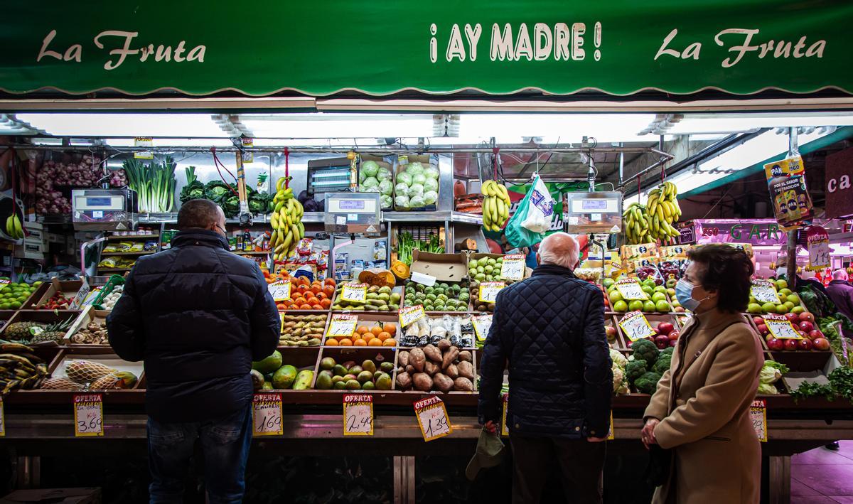 Clientes comprando en una frutería del Mercado de Maravillas en Madrid.