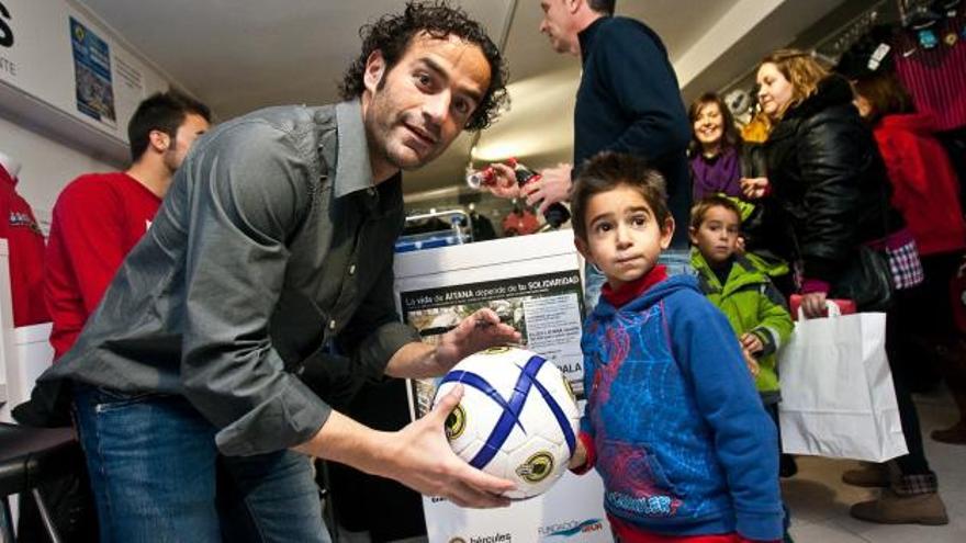 Paco Peña le firma un balón a un niño en un acto promocional del Hércules de Alicante.