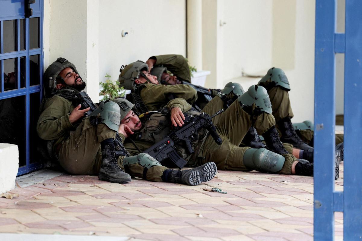 Soldados israelís descansan junto a un edificio, en Sderot, el día después de la entrada masiva de pistoleros de Hamás desde la Franja de Gaza.