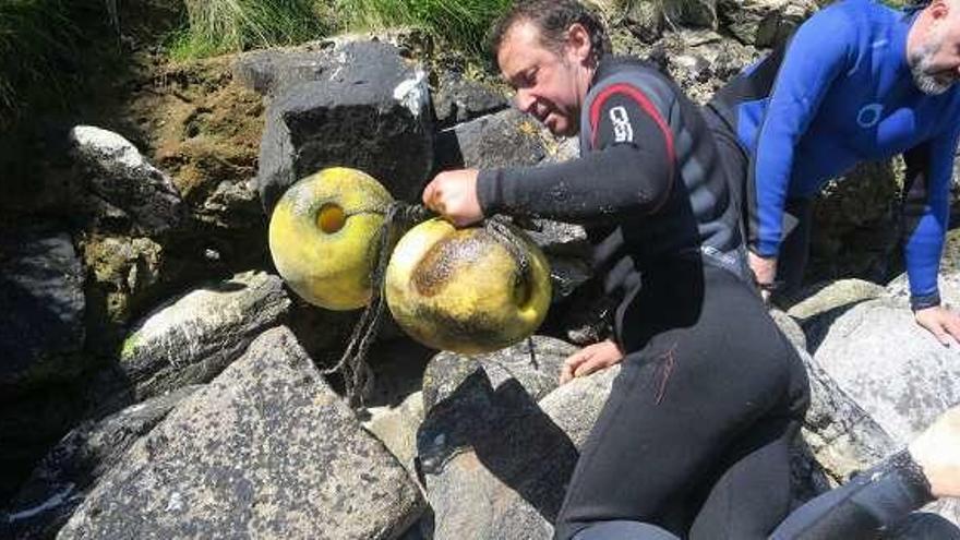 Dos voluntarios retiran restos de entre las rocas de la isla. // J.Corral