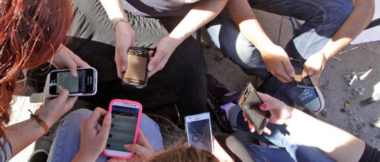 Un grupo de jóvenes consultando sus teléfonos móviles.