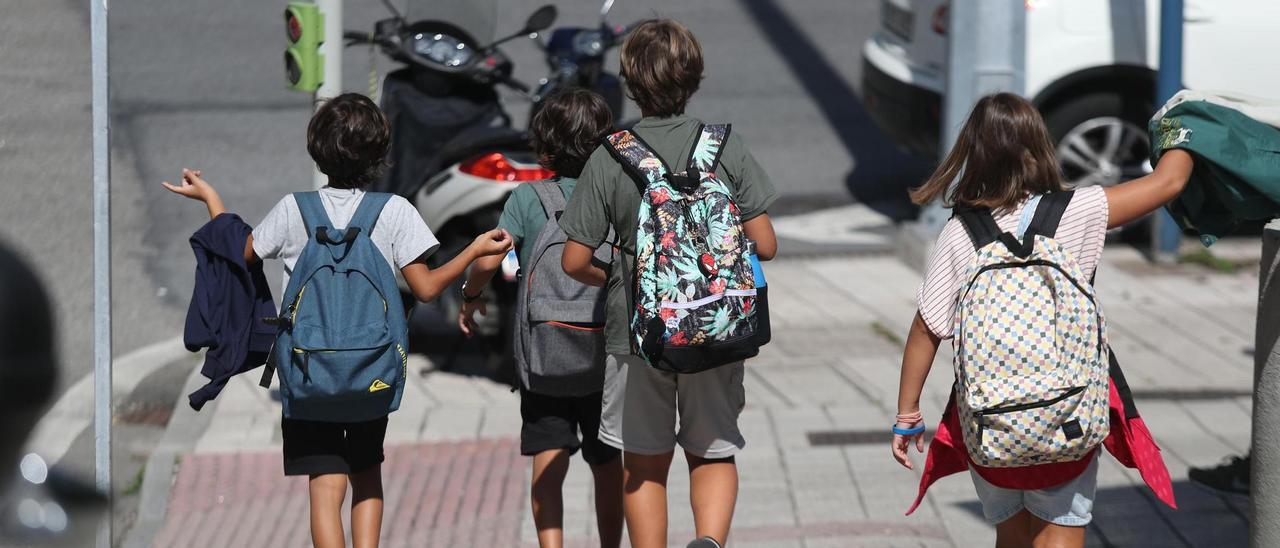 Escolares vigueses se acercan a un paso de peatones regulado por semáforos.