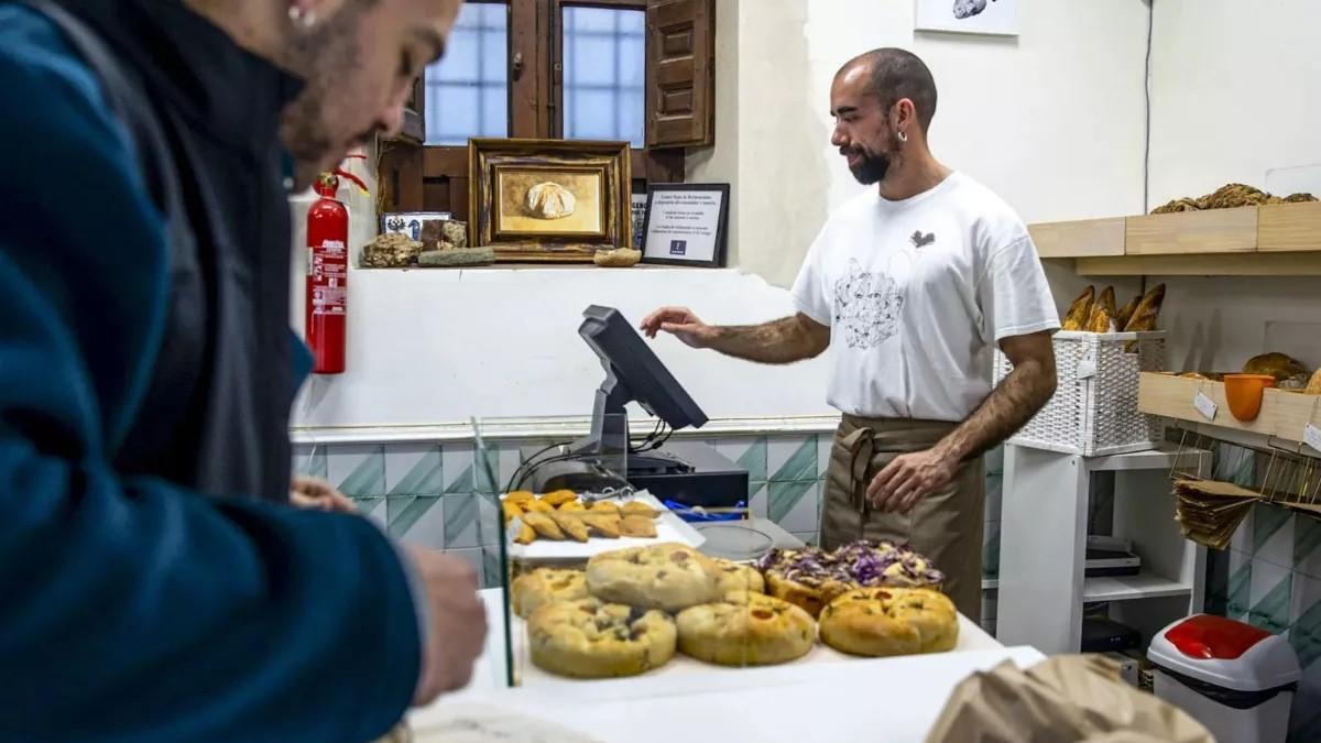 Un autónomo atiende a los clientes en su negocio de panadería.