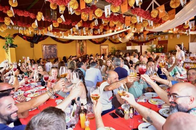 Una caseta llena al mediodía en el recinto ferial con comidas de amigos o compañeros.