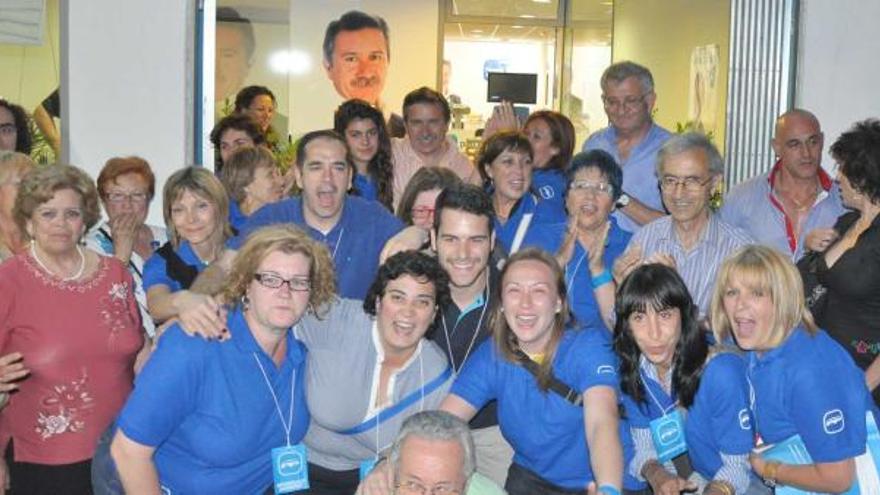 Los populares de Sant Joan celebran el triunfo electoral, con Manuel Aracil en el centro y su cartel electoral al fondo.