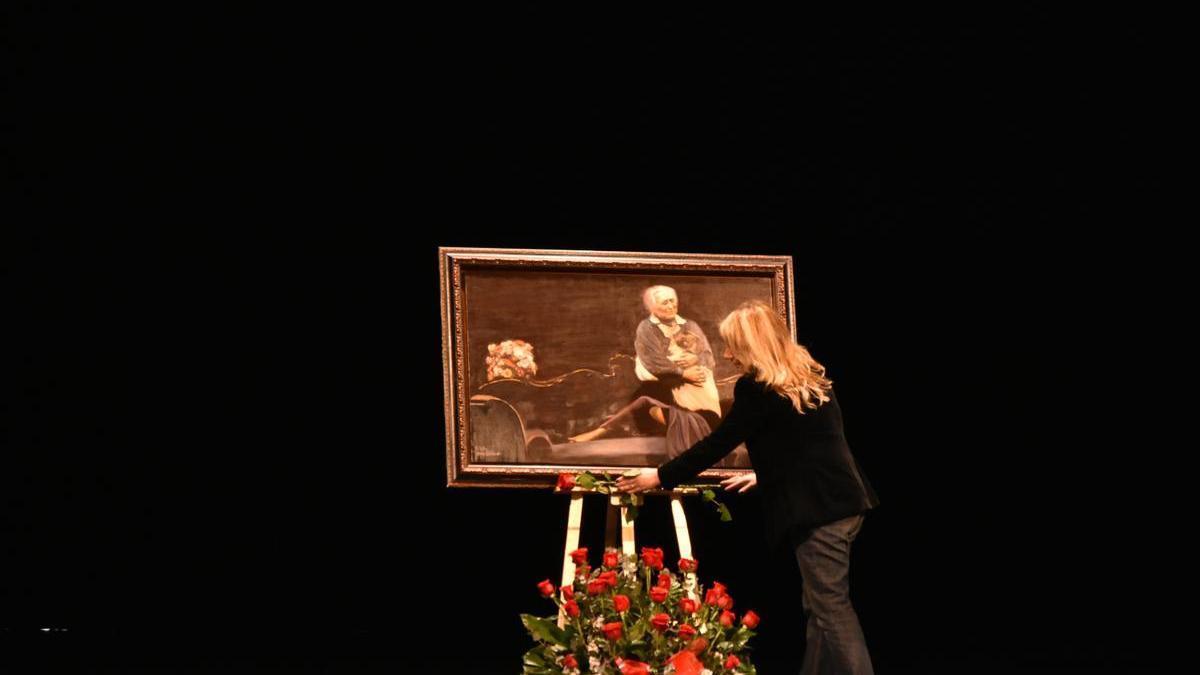 La edil de Cultura, Nines Mazuecos, coloca flores ante el cuadro de Margarita Lozano en el escenario del Guerra, este lunes.