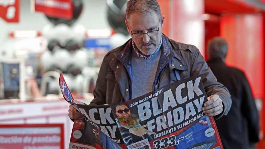 Un ciudadano ojea los productos que promociona un negocio durante el &quot;Black Friday&quot;. // Marta G. Brea