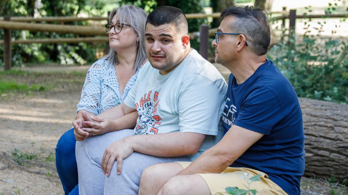 Adrián Lorente, un chico con autismo, sentado en un parque de Cardedeu con sus padres, Eva Velázquez y José Antonio Lorente.