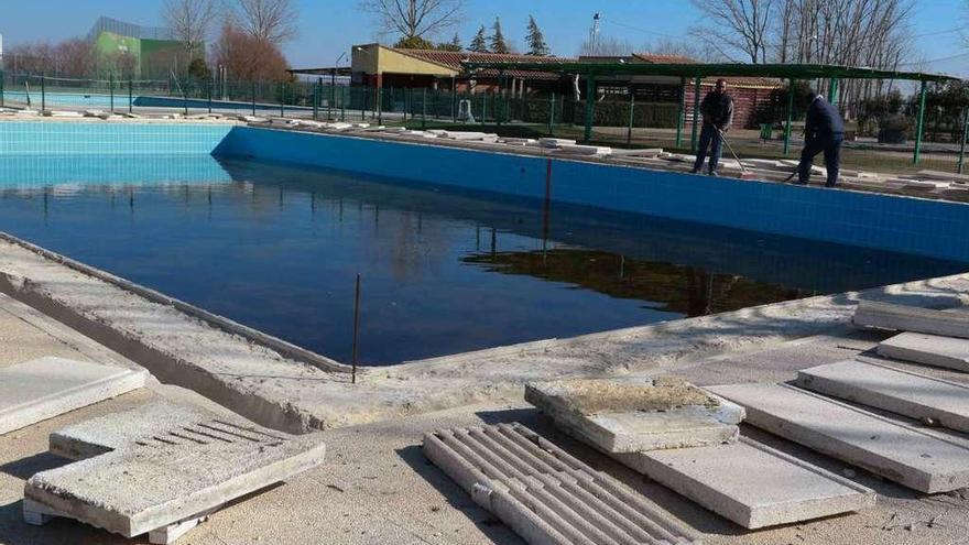 Dos operarios municipales trabajan en las mejoras de la piscina de Villalpando.