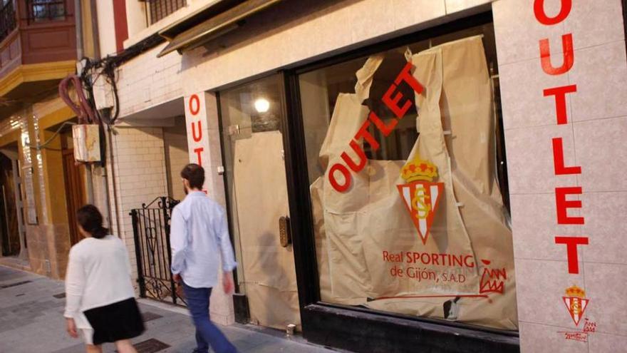 Dos viandantes pasan ante el nuevo &quot;outlet&quot; del Sporting.