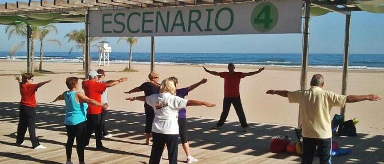 Un grupo del Imserso practica ejercicio frente a una playa de Gandia. | LEVANTE-EMV