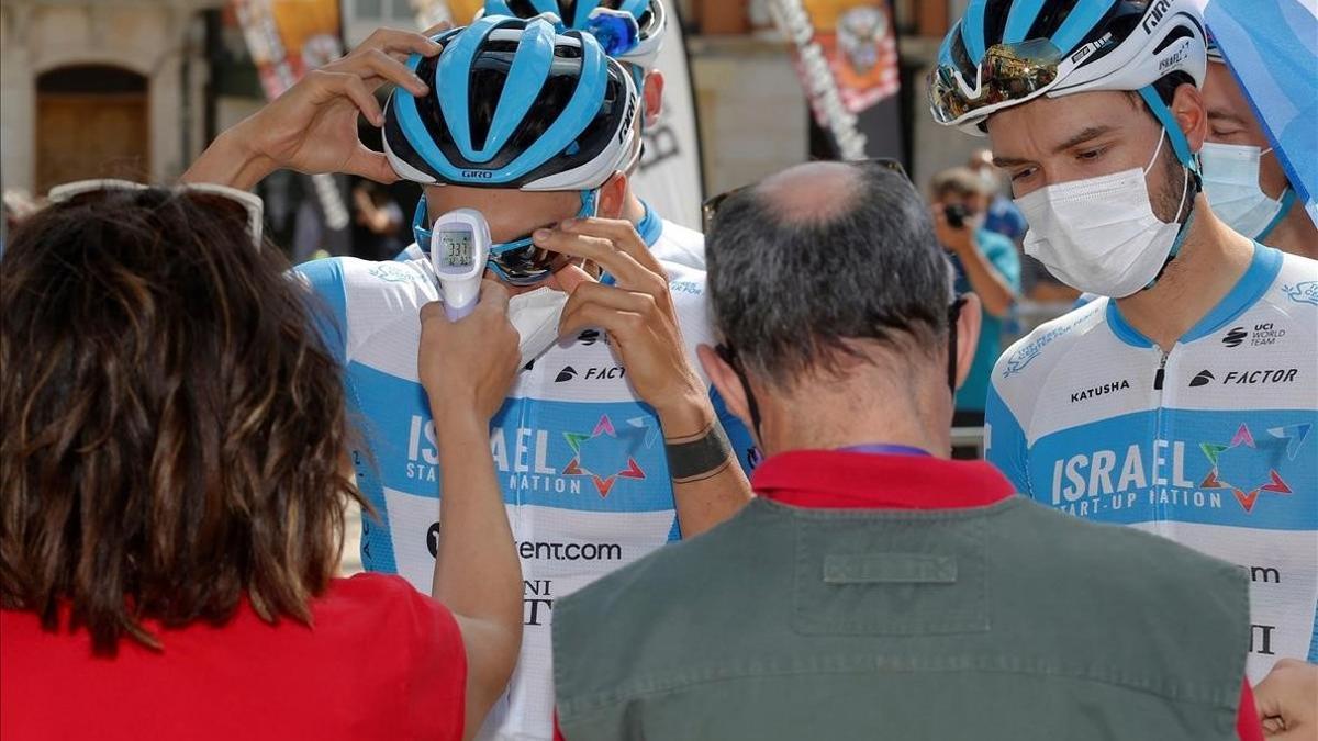 Ciclistas del equipo israelí Start pasan el control de temperatura antes de la salida