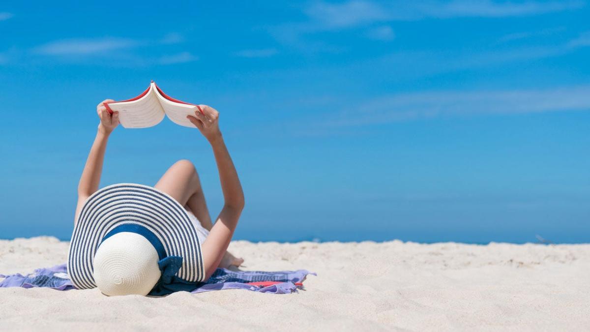 Una mujer lee un libro en la playa