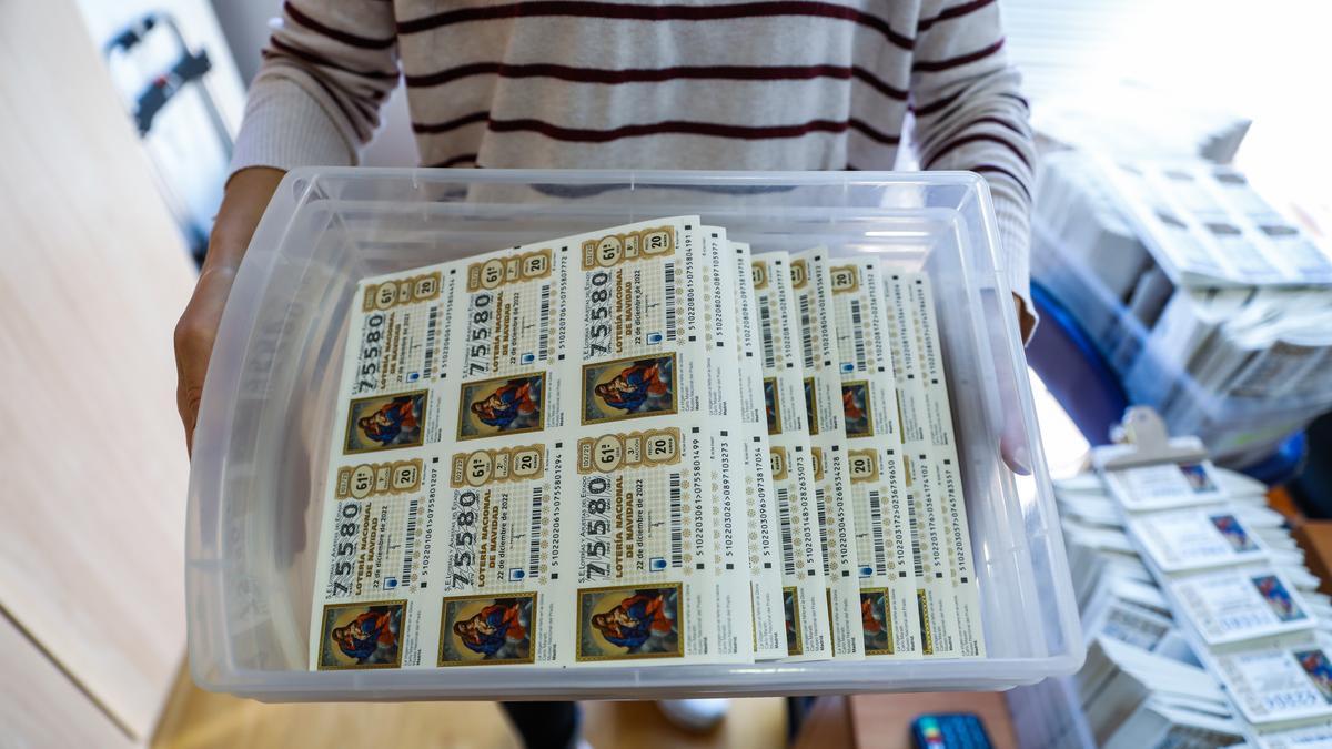 Una trabajadora de una administración de loterías de Barcelona lleva una caja con décimos de la Lotería de Navidad 2022.