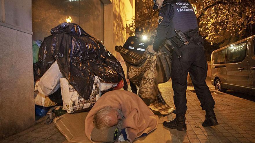 Dos agentes atienden a un sintecho en una calle de València. | ARTURO IRANZO