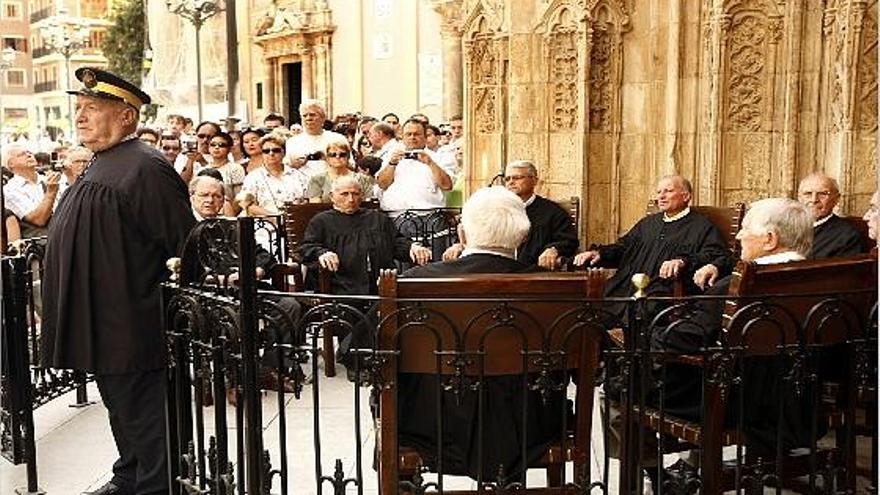 Sesión del Tribunal de las Aguas, en la puerta de los Apóstoles de la catedral de Valencia; al fondo, los turistas toman fotos.