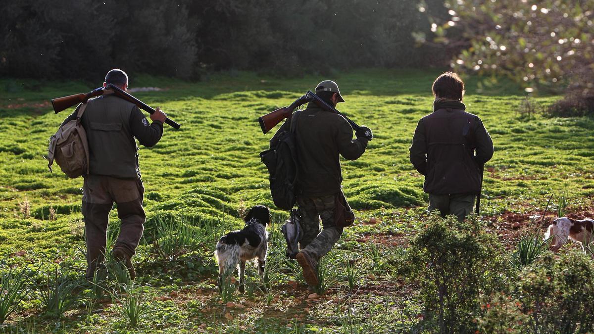 Tres cazadores acompañados de un perro.