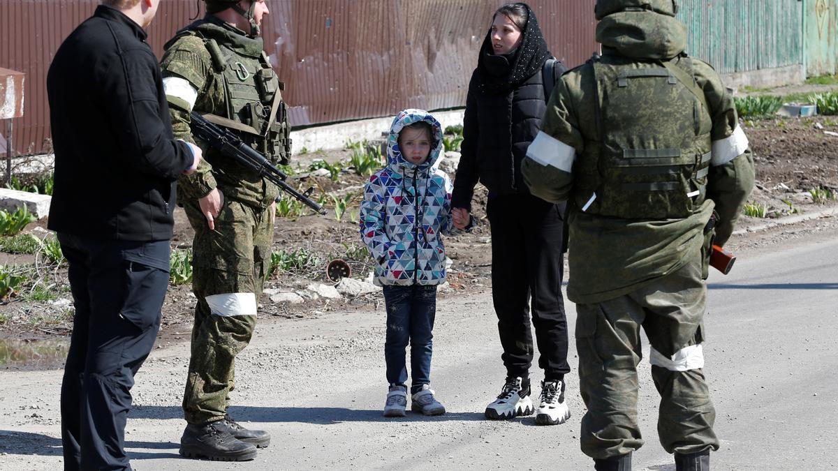 Una mujer con un niño habla con miembros del servicio de las tropas prorrusas.