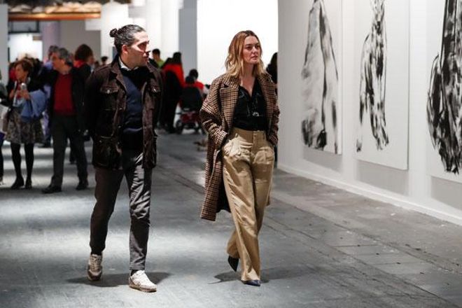 Marta Ortega con camisa negra y abrigo de cuadros de Zara, y pantalones de pata de elefante