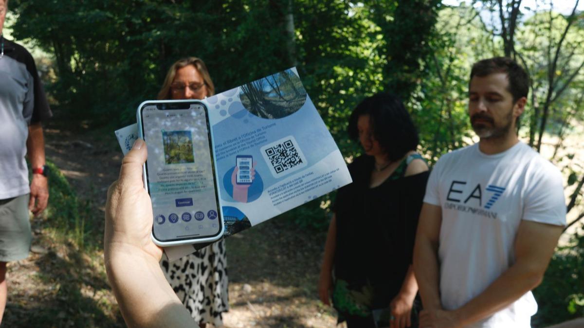 Un mòbil amb el projecte Vorater en pantalla i participants en un exercici de relaxació | ACN