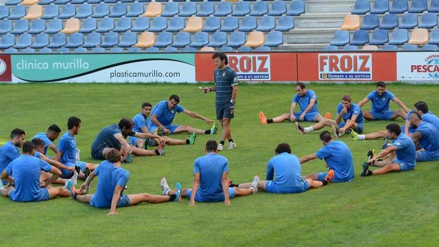 Los jugadores estiran durante un calentamiento con el preparador fícico Roberto Valdés, ante la mirada de Luisito. // Rafa Vázquez