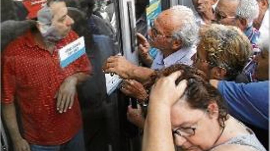 Un grup de jubilats fent cua davant un banc grec.