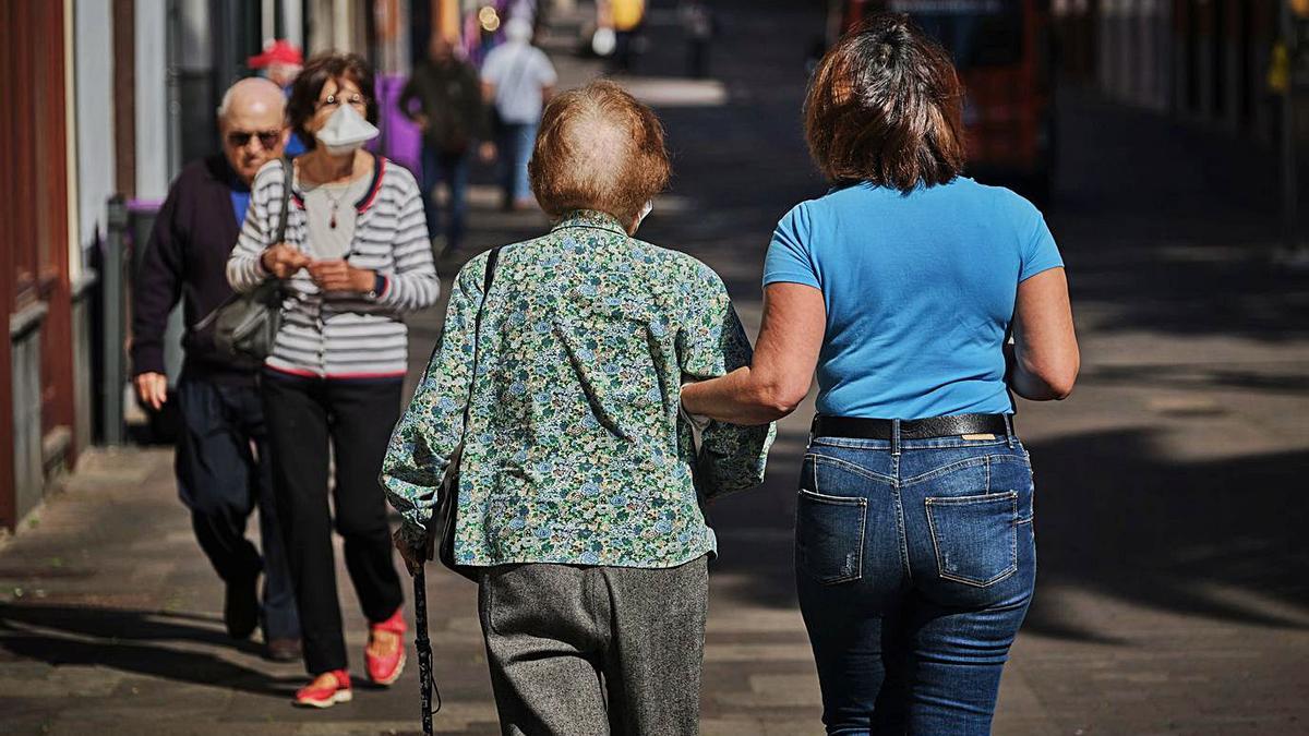 Una mujer mayor pasea junto a su cuidadora.