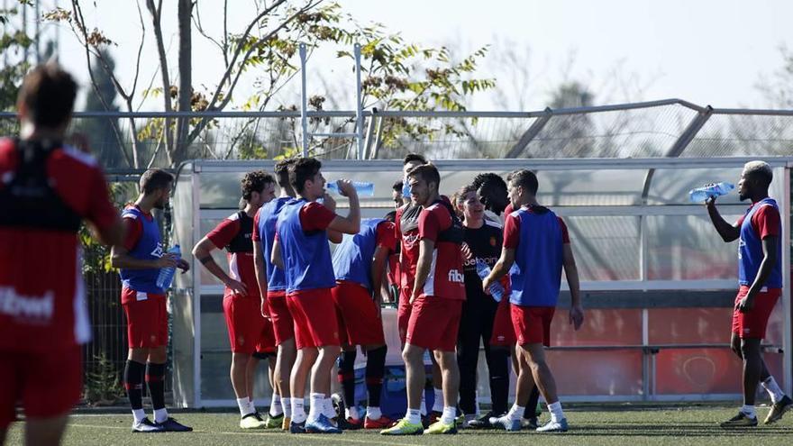 Los jugadores del Mallorca se refrescan tras ejercitarse en el campo de césped artificial.