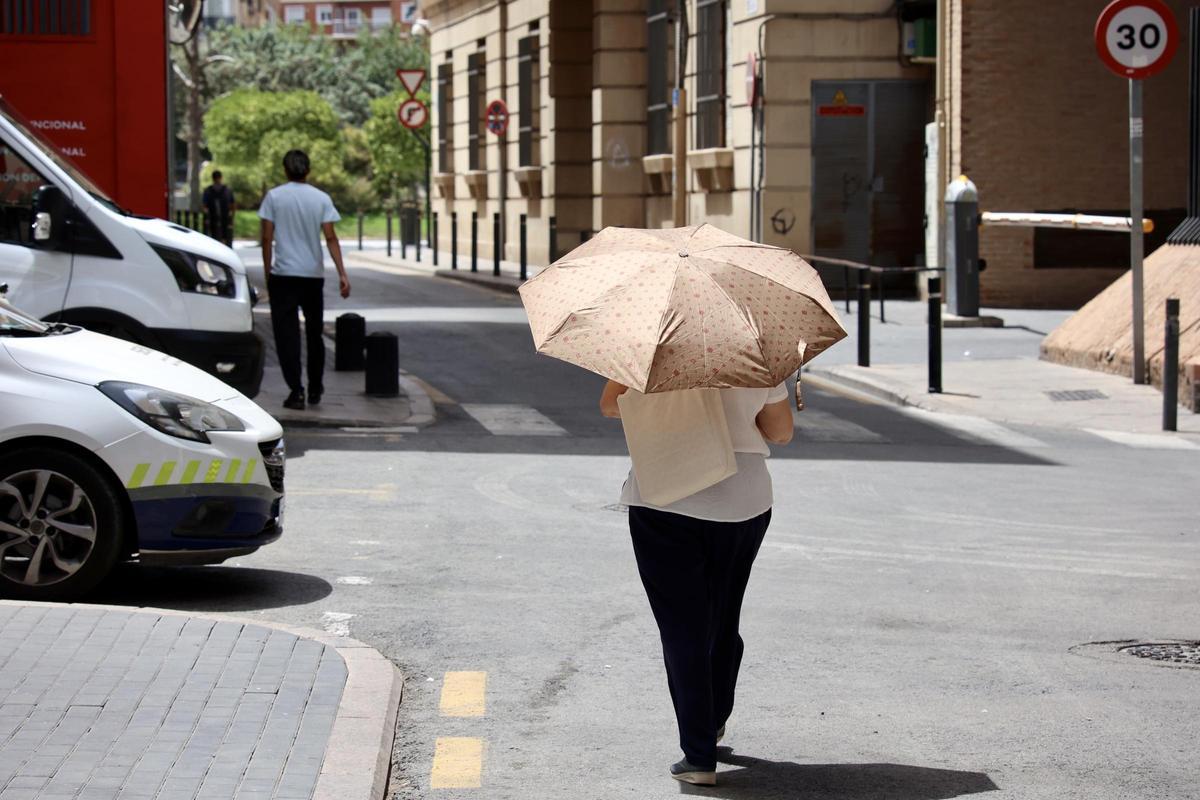 Una mujer camina por Murcia con su paraguas en medio de una ola de calor.