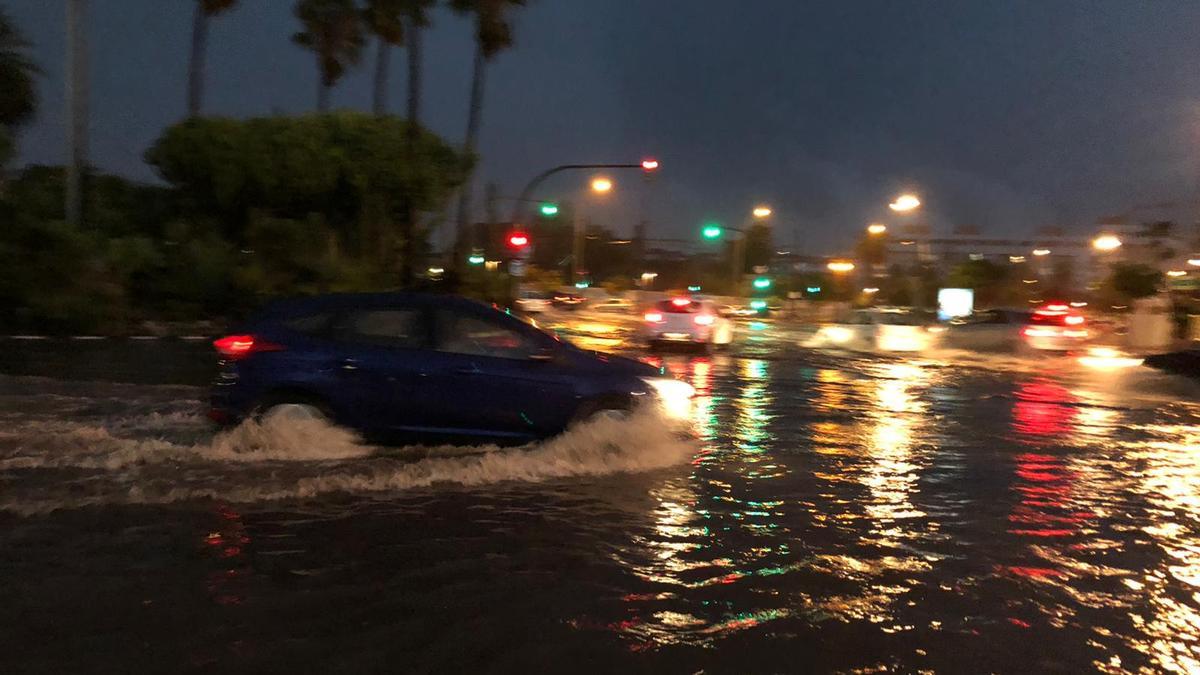 Un coche en la rotonda de la avenida de los Naranjos, completamente inundada por las lluvias que ha dejado el tiempo en Valencia.