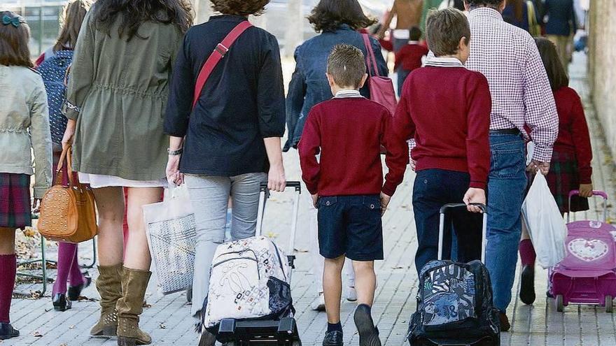 Varios menores de edad se dirigen al colegio con sus padres.