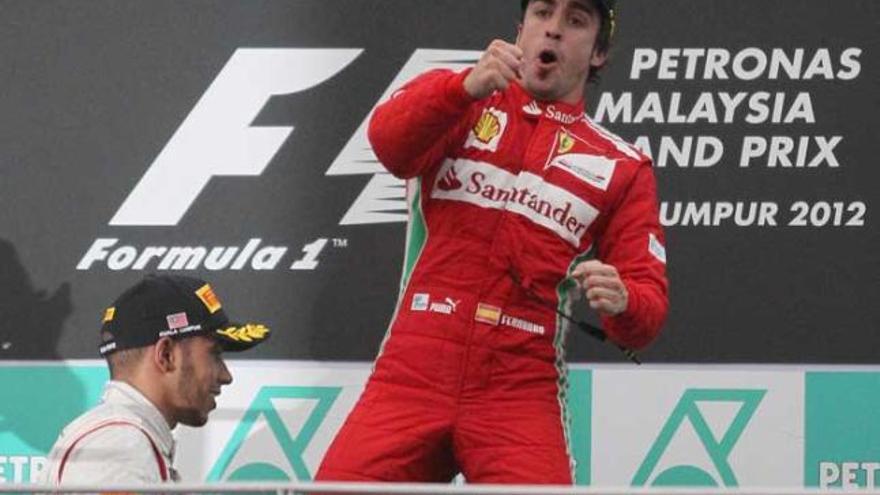 Alonso celebra en el podio su victoria en el GP de Malasia, con Hamilton a la izquierda de la imagen.| reuters