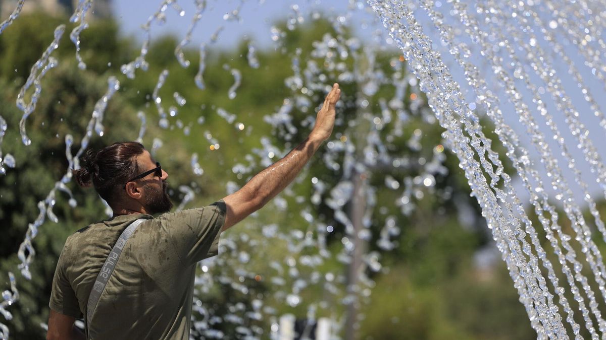 Un hombre se refresca en una fuente.