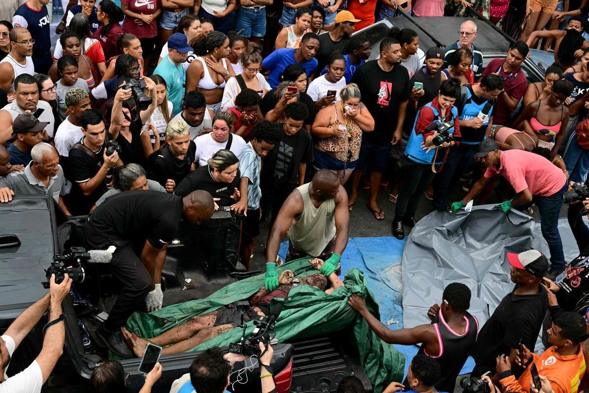 EDITORS NOTE: Graphic content / Residents carry a dead body on Sao Lucas Square of the Vila Cruzeiro favela at the Penha complex in Rio de Janeiro, Brazil, on October 29, 2025, in the aftermath of Operacao Contencao (Operation Containment). Residents of a favela in Rio de Janeiro lined up more than 50 bodies at a plaza in their low-income neighborhood on Ocotber 29, a day after the bloodiest police operation in the citys history, AFP reported. (Photo by Pablo PORCIUNCULA / AFP). Graphic content