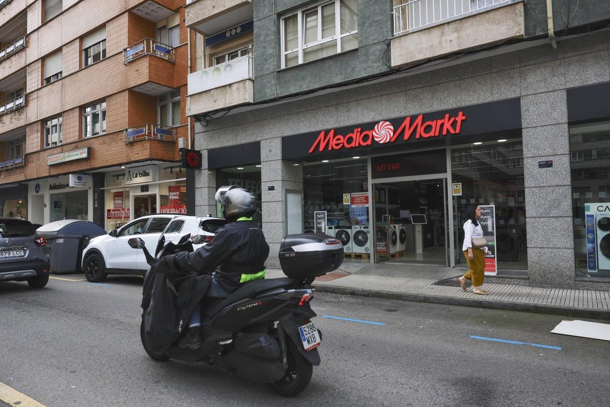 Una moto pasa por delante de la nueva tienda de Media Markt en Avilés.