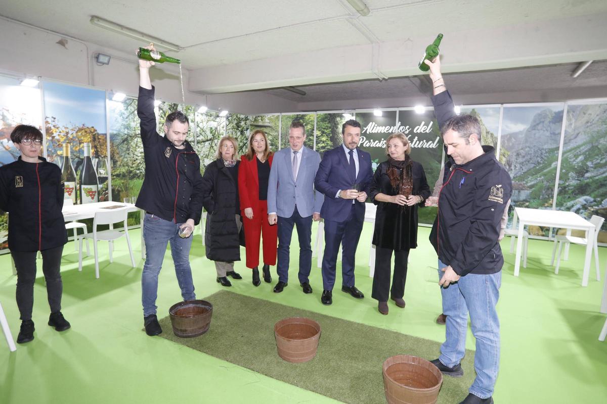 Celia Fernández, Begoña López, Marcelino Marcos, Daniel González y Mariví Monteserín, con dos escanciadores echando sidra en el stand de Alimentos del Paraíso