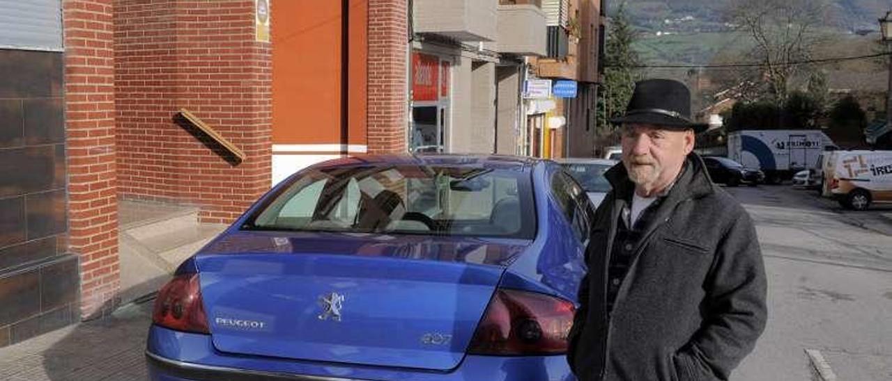 Froilán Álvarez, posa junto al vehículo que acaba de estacionar junto a una parada de autobús.