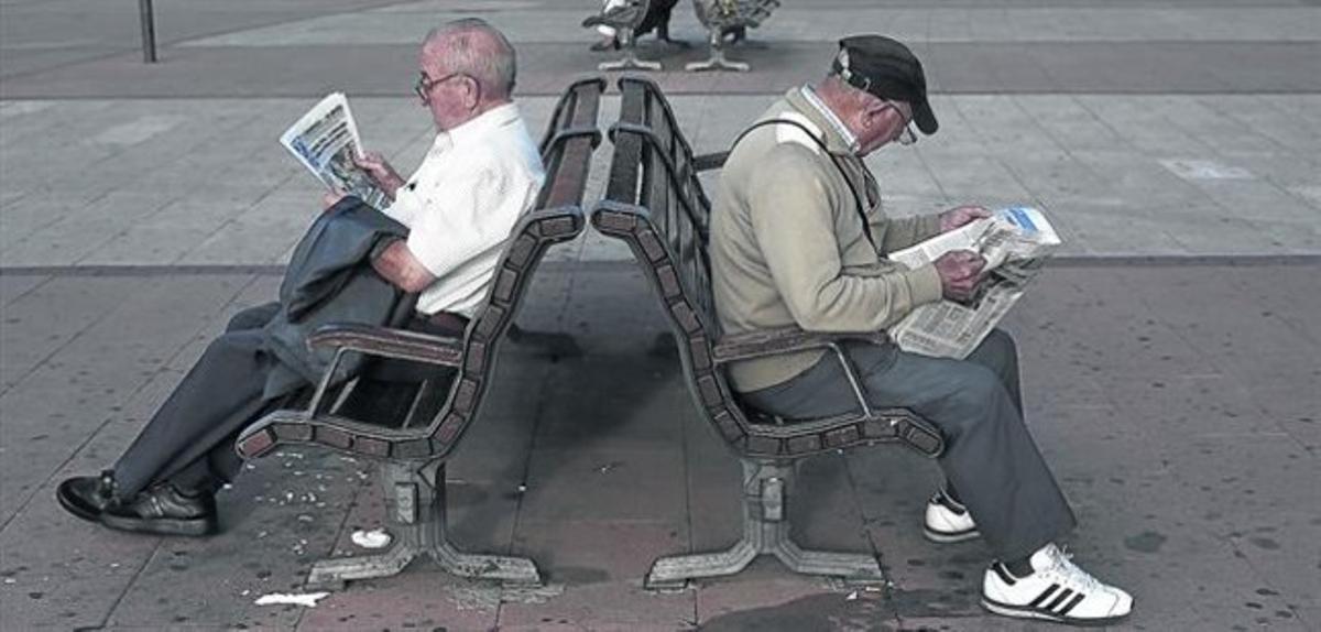 Dos jubilados leen la prensa en un parque.