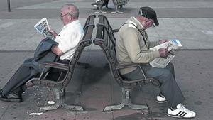 Dos jubilados leen la prensa en un parque.